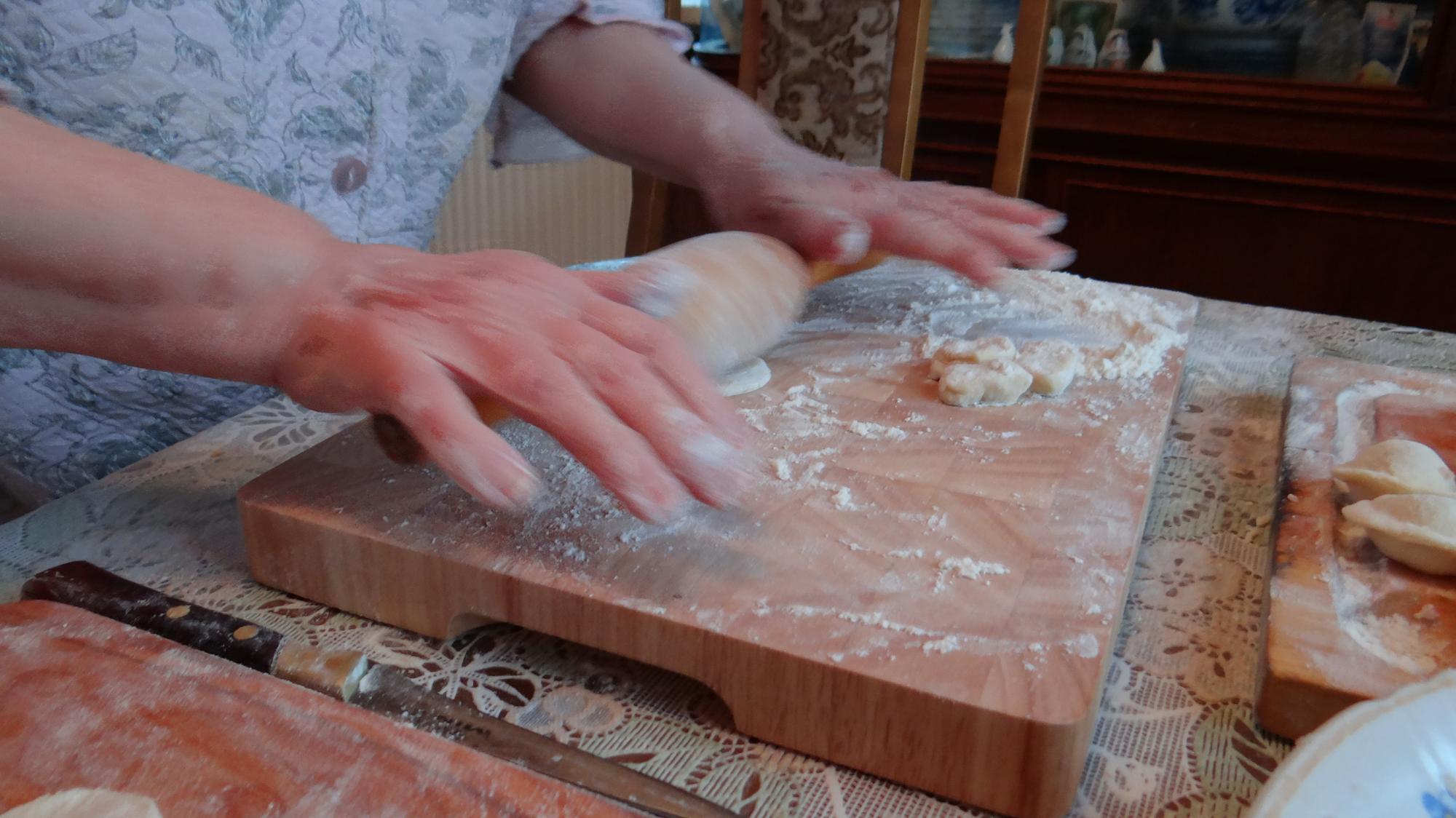Hands preparing dough on wooden board